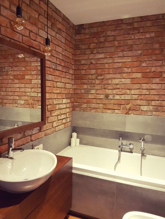 a minimalist meets industrial bathroom with red bricks, grey tiles and a rich-toned vanity