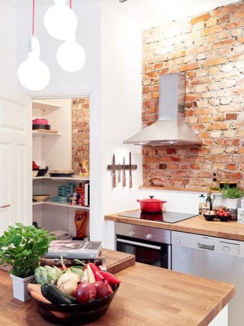 a modern farmhouse kitchen with white cabinets, shiny metal appliances and red brick walls