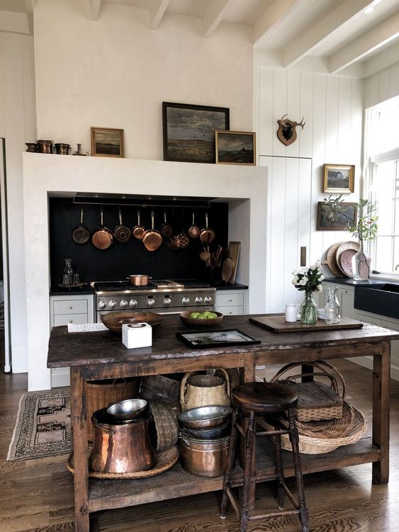 a modern farmhouse white kitchen with wooden beams on the ceiling, a vintage stained kitchen island and a matching stool