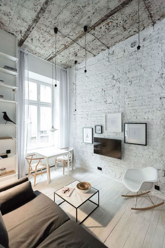 a monochromatic living room with a white brick wall and a rough ceiling for a touch of drama