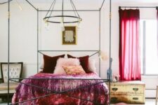 a neutral eclectic bedroom done with catchy gold and black furniture, bold red curtains, burgundy and red bedding and a colorful rug