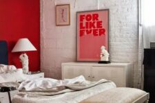 a red accent wall is a bold statement in this white and off-white bedroom and an artwork matches