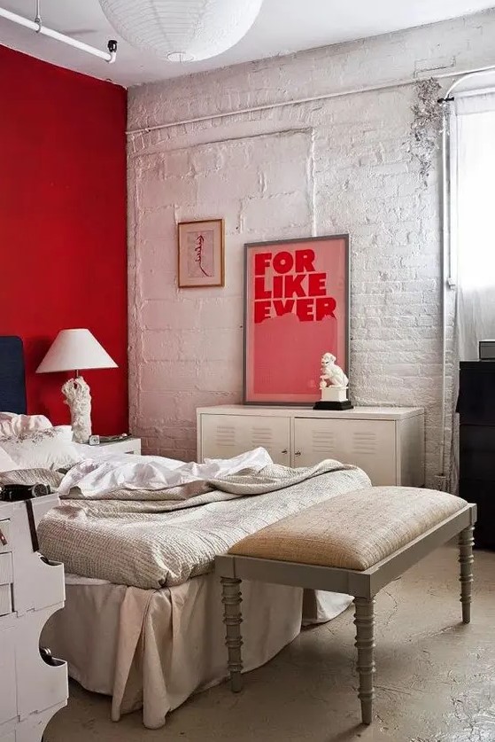 a red accent wall is a bold statement in this white and off-white bedroom and an artwork matches