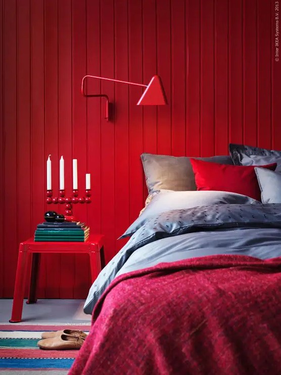 a red wooden plank wall, a matching sconce and a nigthstand create a super colorful space