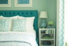 a retro-inspired aqua bedroom with a turquoise upholstered bed and printed bedding and a rug, a nightstand with books