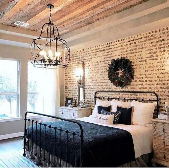 a rustic meets vintage bedroom with a faux brick wall, a forged chandelier and elegant dressers