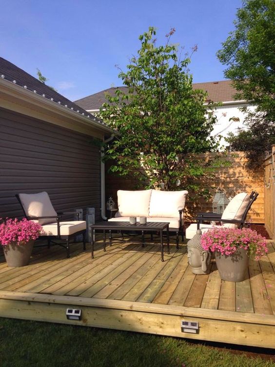 a small deck with a contemporary feel, contrasting contemporary furniture and potted blooms