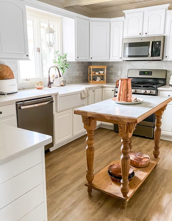 a small white kitchen with vintage-styled cabinets, a grey tile backsplash and a vintage wooden kitchen island