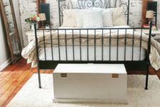 a vintage bedroom with a faux whitewashed brick wall that adds texture to the space and a rich stained wooden floor