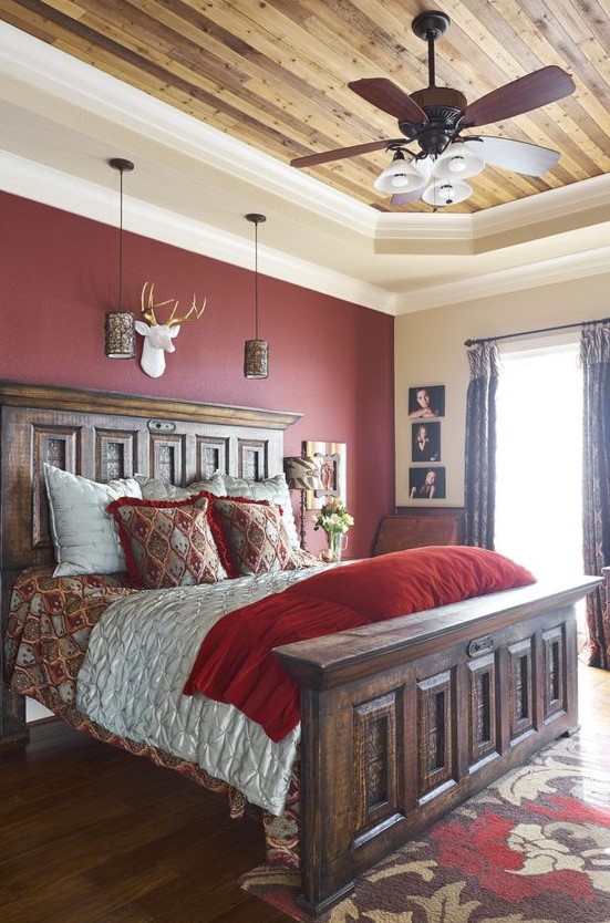a vintage rustic bedroom with a burgundy statement wall, heavy wooden furniture, pendant lamps, vintage refined bedding and printed textiles