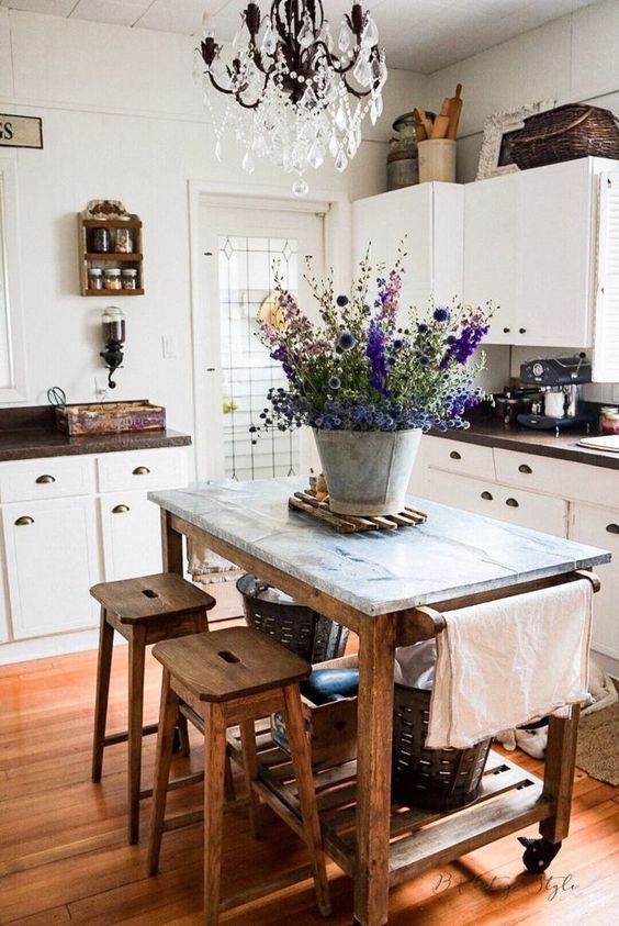 a white cottage kitchen with shaker style cabinets, dark countertops, a vintage wooden kitchen island with a stone countertop