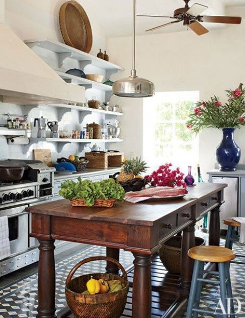 a white farmhouse kitchen with open shelves instead of upper cabinets, stainless steel applainces and a dark stained vintage table as a kitchen island