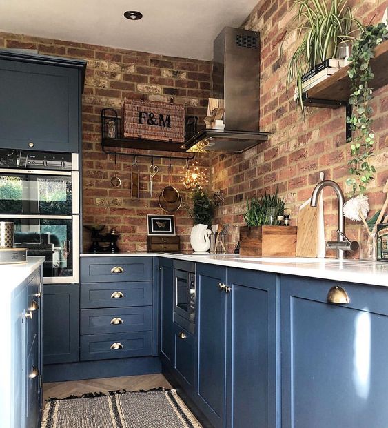 blue kitchen cabinets with white countertops and red brick walls is a bold contrasting idea with a touch of chic