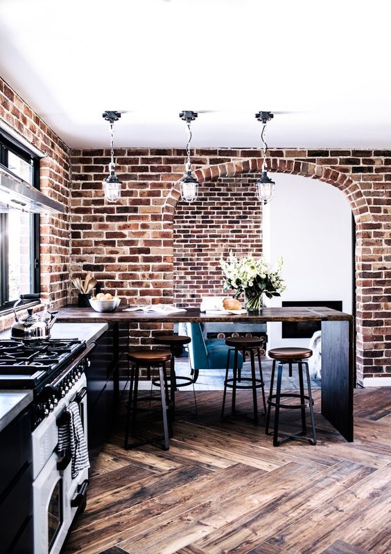 bold red brick walls, stained chevron clad floors and rich stained furniture for an industrial meets rustic kitchen
