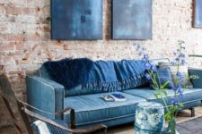 navy furniture and pillows plus artworks contrast the red brick wall and a wooden floor