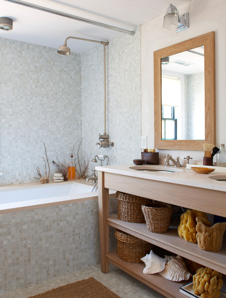 a contemporary ocean-inspired bathroom with light blue tiles, baskets, sponges and seashells  (Rosenberg Kolb Architects)