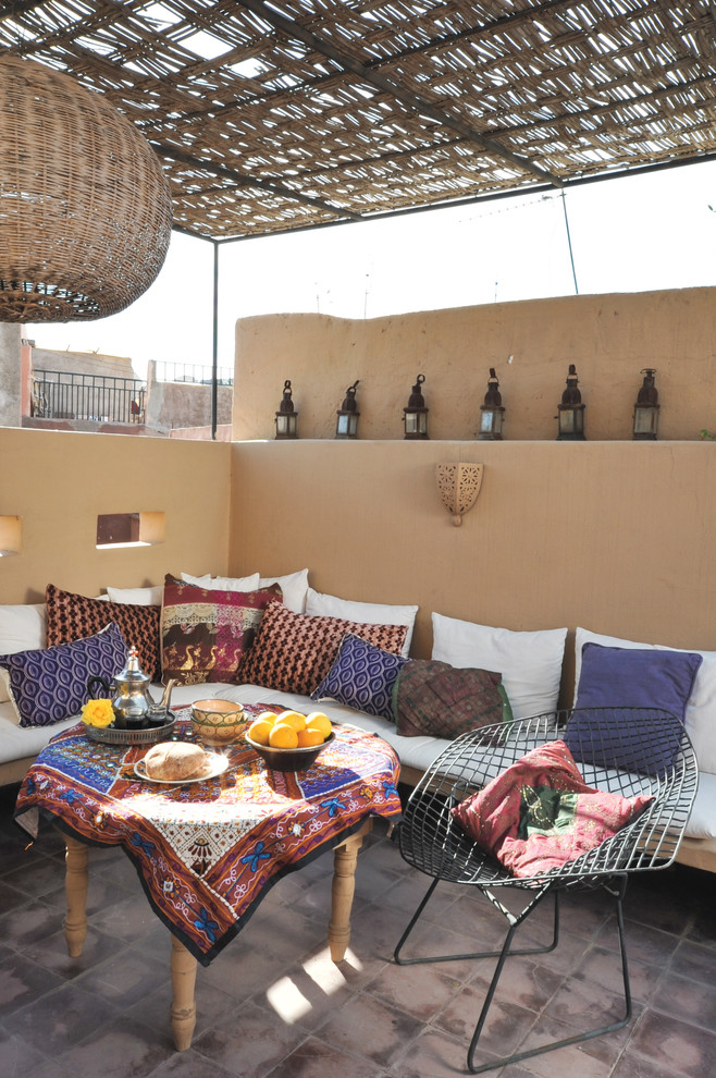 a rooftop patio with sandy walls, a large L-shaped sofa, colorful pillows and a bright tablecloth  (Artisan Books)