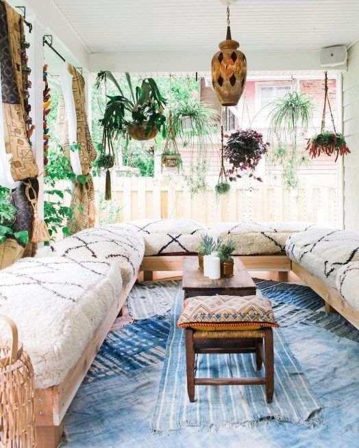 a Moroccan patio with a U-shaped sofa, blue rugs, potted greenery hanging and low furniture