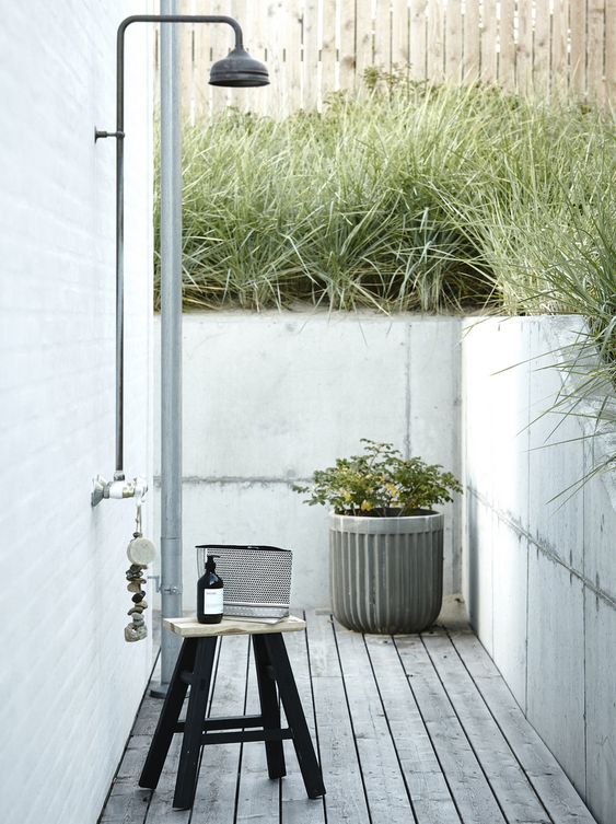 a Scandinavian outdoor shower with a concrete planter, stools and some accessories