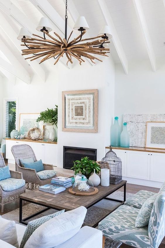 a beach living room with touches of blue and turquoise, printed furniture, a driftwood chandelier and an artwork