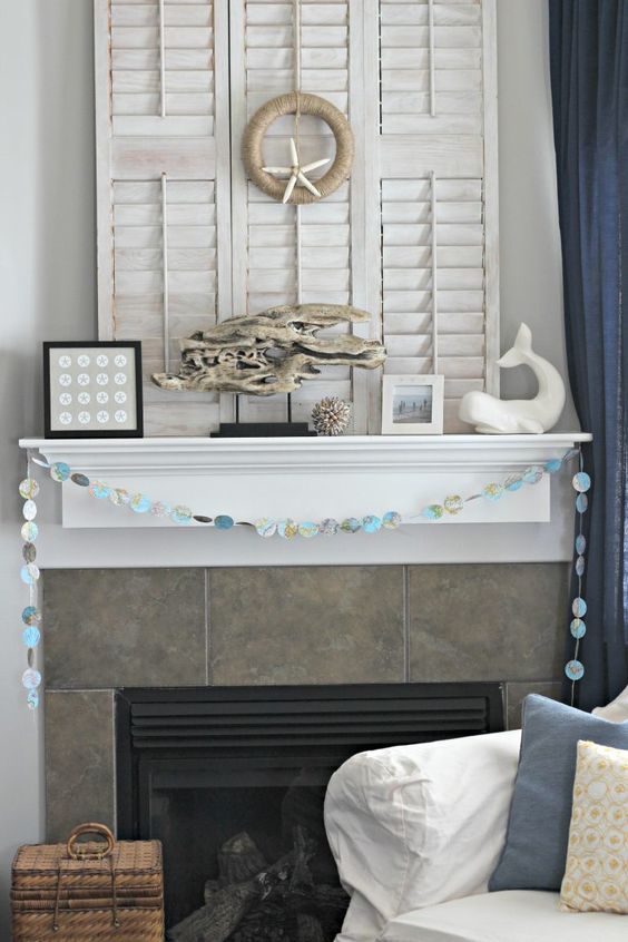 a beach mantel with a little seashell artwork, a whale figurine, a driftwood piece and a seashell ball