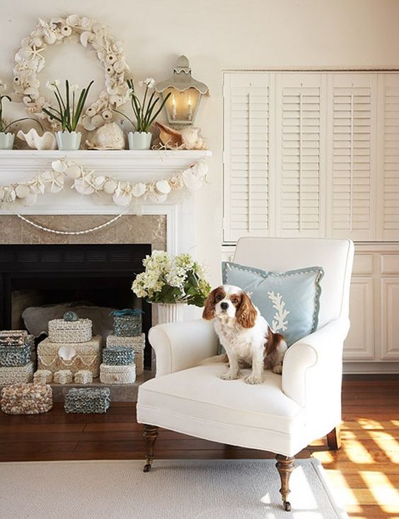 a beach mantel with a seashell and urchin wreath, potted blooms, large shells and a seashell and starfish garland