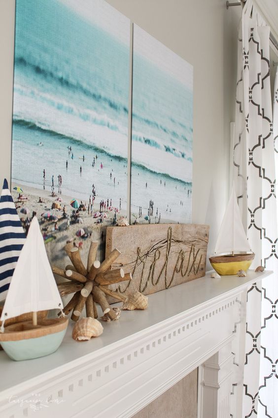 a beach mantel with seashells, two cute boats, a wooden sign and a gorgeous double beach artwork over it
