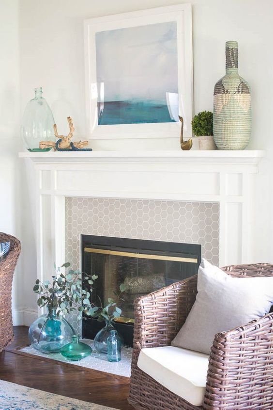 a beachy mantel with a seaside artwork, driftwood, blue beads, a green bottle, boxwood and a yarn wrapped bottle
