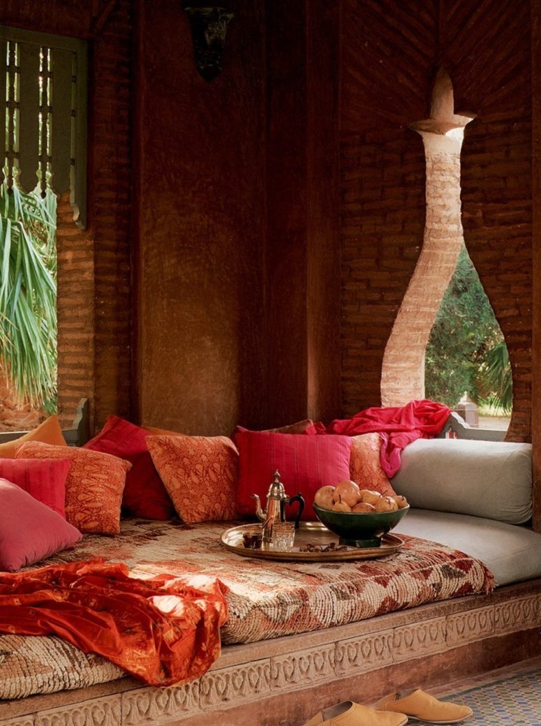 a beautiful and colorful Moroccan patio with a carved wooden daybed, bright and printed textiles and a tray with coffee
