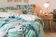 a boho tropical bedroom with rattan and cane furniture, a macrame hanging, bright tropical print bedding and a fluffy rug