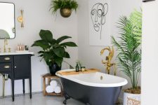 a bold tropical bathroom in neutrals, with a black vanity and a tub, potted greenery, gold touches and a pink stool
