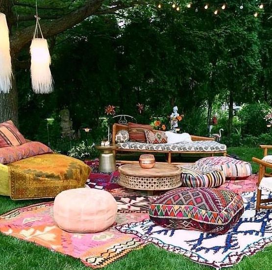 a bright Moroccan lounge with lots of boho rugs, floor cushions and ottomans, bright furniture and fringe lanterns