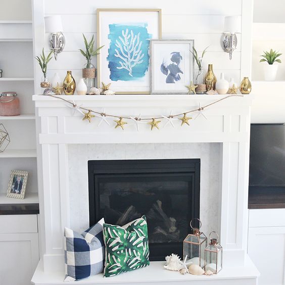 a bright beach mantel with a starfish garland, colro block vases, seaside artworks and succulents