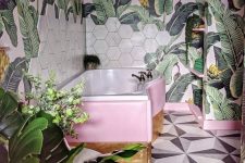 a bright tropical bathroom with banan leaf wallpaper, marble hex tiles, a pink and gold clad bathtub is lovely