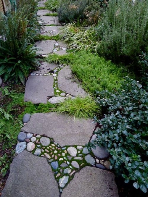 a catchy and bold stone garden path with moss, smaller rocks in betwee and some grasses growing