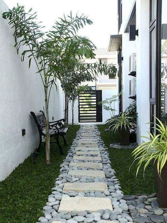 a catchy and natural garden path of grey large scale pebbles and stone tiles on top