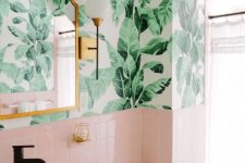 a chic tropical bathroom wiht tropical wallpaper, pink tiles, a bowl sink and touches of brass