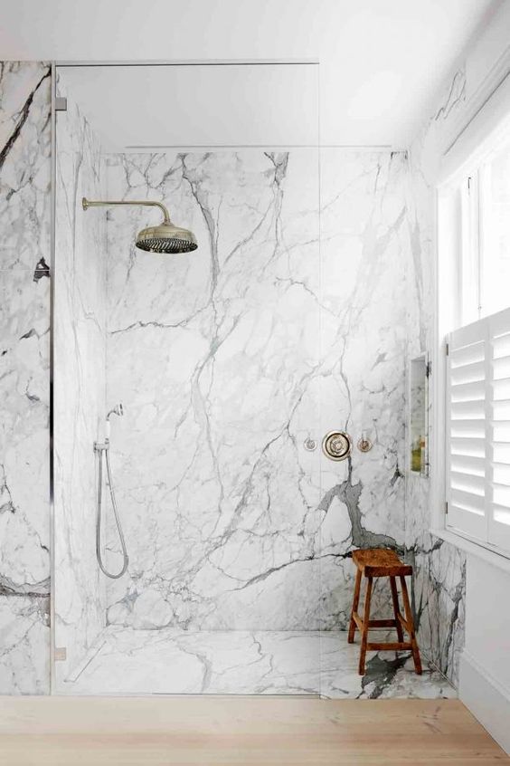 a contemporary bathroom with white marble, sleek wood and vintage hardware for a bright and chic look