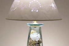 a cool table lamp with a glass base with seashells, starfish and beach sand inside and a printed lampshade for a beachy space