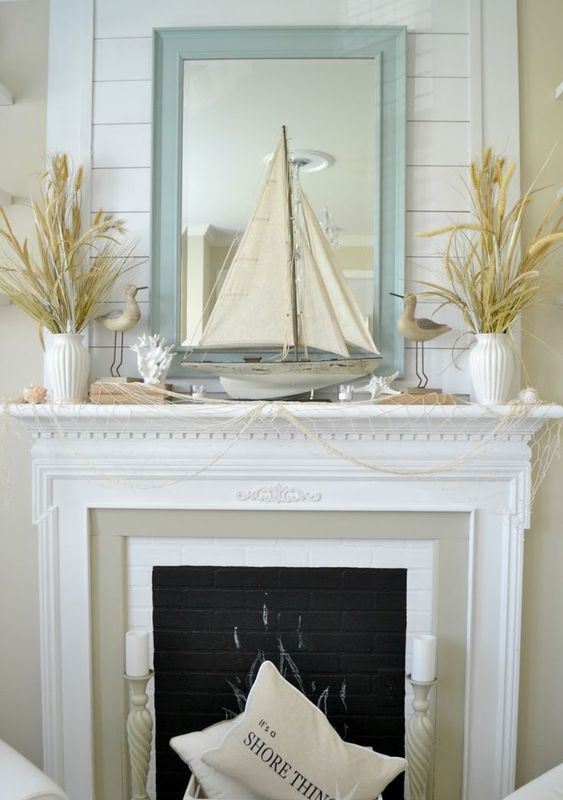 a fun beach mantel covered with net, some dried herbs in vases, corals, starfish, candles, birdies and a large boat in the center