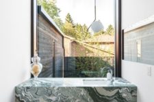 a green marble modern vanity in a small powder room with a view to the courtyard