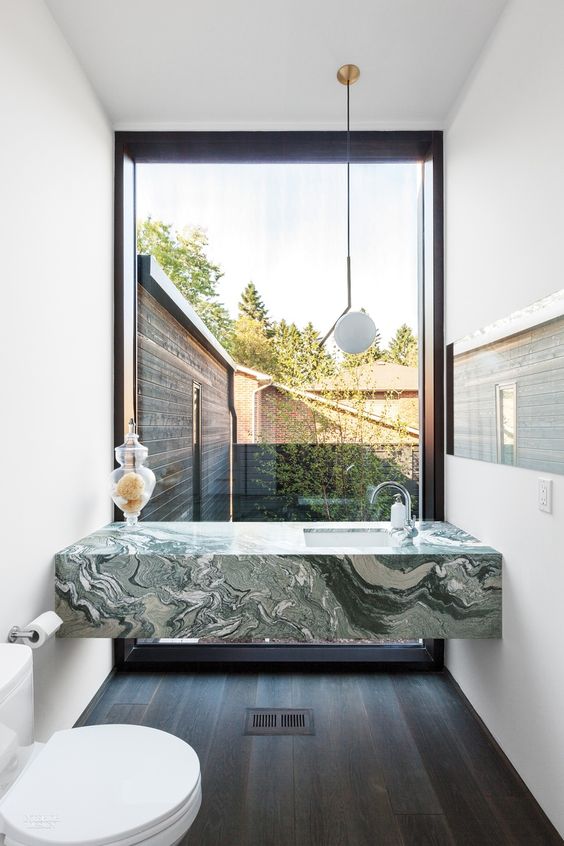 a green marble modern vanity in a small powder room with a view to the courtyard