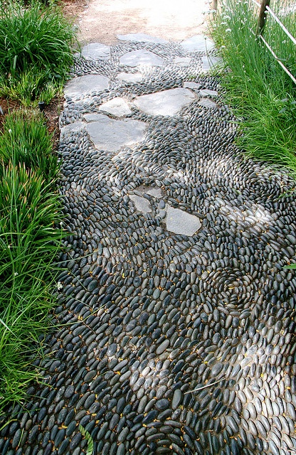 a grey pebble garden path with a chaotical pattern and some stones incorporated is a cool natural idea