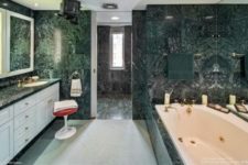 a large modern bathroom clad with green marble tiles is made fresher with white furniture and cabinets