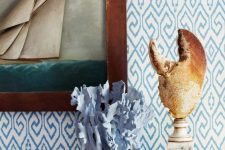 a lobster claw on a marble stand, a blue painted coral, seashells and a seaside artwork for a beachy mantel