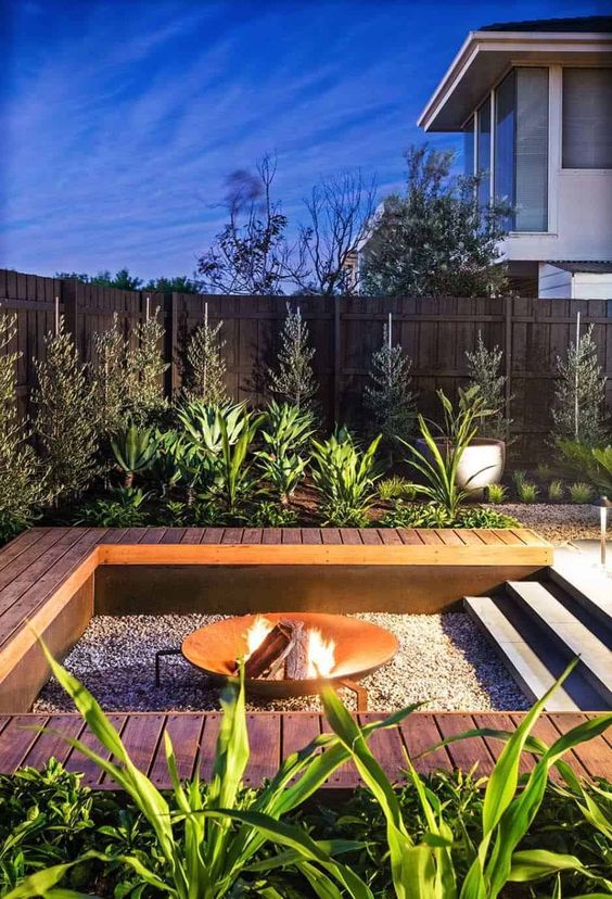 a lovely fire pit with a built-in wooden deck or bench, with an open wrought metal fire bowl that welcomes