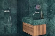 a minimalist bathroom fully covered with green marble tiles that are contrasting light-colored wood