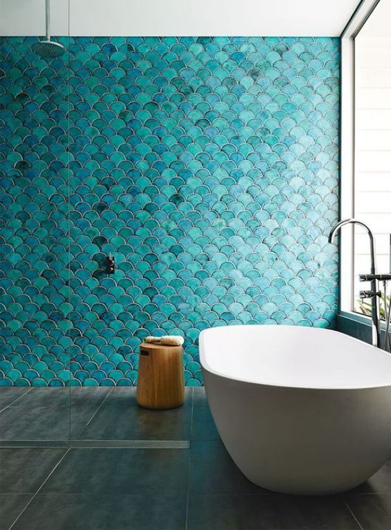 a minimalist bathroom inspired by the sea, with turquoise fish scale tiles and an oval bathtub