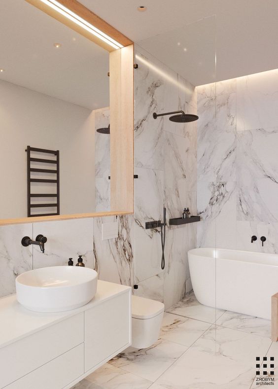 a minimalist space done with white marble, a large lit up mirror, a floating vanity and touches of black