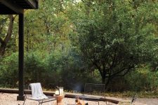 a modern and lovely outdoor space with a black wrought iron fire bowl, metal chairs, a cork table and potted plants